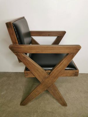 une chaise en bois avec une assise en cuir noir, dans un coin de la pièce