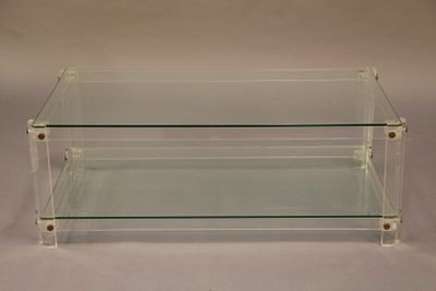 table basse en verre transparent avec trois étagères superposées sur fond blanc