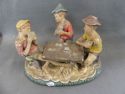 three figurines of men playing cards at a table