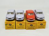 four toy cars are lined up in a row on a white surface