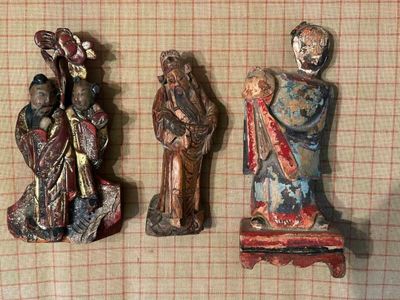 trois figurines représentant des personnes sont disposées sur une nappe à carreaux