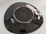 a black plate with a gold rim sitting on a white table