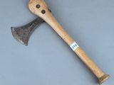 une vieille hache avec un manche en bois posée sur une surface grise