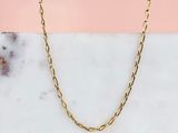 a close up of a gold chain necklace on a marble surface