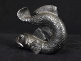 silver fish statue on black background with a black background