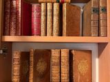 de nombreux livres anciens posés sur une étagère en bois dans une pièce