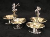 three silver plated candlesticks on stands on a black background