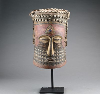 un masque en bois posé sur un socle, sur fond gris