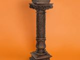 an antique cast iron pedestal stands against an orange background