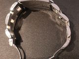 someone is holding a watch on their wrist on a black surface