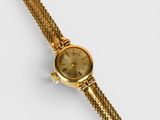 a close up of a gold watch on a white surface
