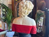 a statue of a woman in a red dress sitting on a pedestal