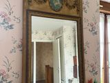 un miroir posé sur un bureau dans une pièce au papier peint à motifs floraux