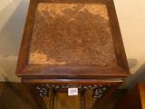 a small wooden table with a marble top on a carpeted floor
