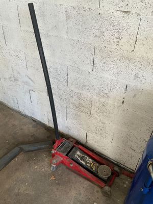 an image of a garage with a blue car and a red jack
