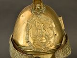 an old helmet with a gold decoration on it on a stand
