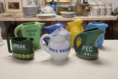 many different colored pitchers sitting on a table