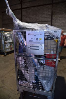 une cage métallique sur laquelle est accrochée une pancarte, dans un entrepôt