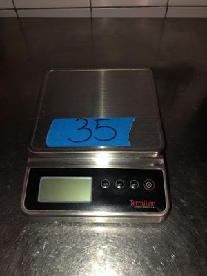 une balance sur laquelle est collé un autocollant bleu, posée sur un comptoir