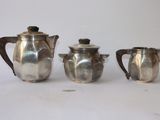 trois théières en argent et une cafetière sur une table