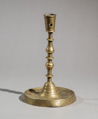 brass candle holder with a candle in the middle of it