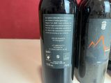 two bottles of red wine sitting on a table next to each other