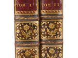 two old books are stacked on top of each other on a white surface