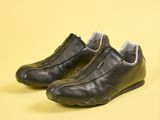 une paire de chaussures en cuir noir avec des fermetures éclair, sur fond jaune