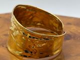 gold hammered ring on a wooden table with a white background