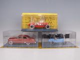 three toy cars in a display case on a white surface