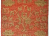 an orange and gold rug with a floral design on it