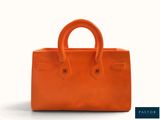 a close up of an orange handbag on a white background