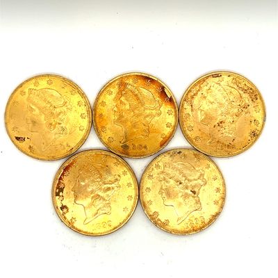quatre pièces d'or sont empilées les unes sur les autres sur une surface blanche