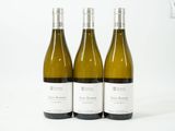 trois bouteilles de vin blanc posées l'une à côté de l'autre sur une surface blanche