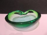 un saladier en verre vert posé sur une table blanche