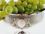 a silver bowl filled with green grapes on top of a table