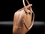 a close up of a tan handbag on a black background
