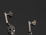 une paire de boucles d'oreilles en forme de crâne en argent, avec une tige au milieu