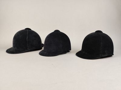 trois chapeaux sont alignés les uns à côté des autres sur une surface blanche