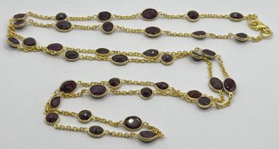 un gros plan d'une chaîne en or ornée de pierres violettes
