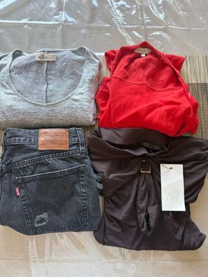 trois paires de jeans et un t-shirt posés par terre