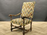 une chaise en bois avec une assise rembourrée à motifs, posée sur un parquet