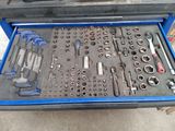 une boîte à outils bleue remplie d'outils, posée par terre