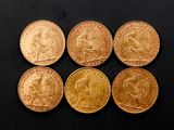 six souverains d'or de tailles et de formes différentes posés sur une surface noire
