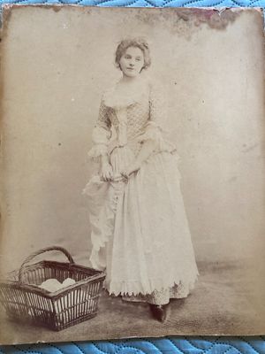 an old photo of a woman in a dress with a basket