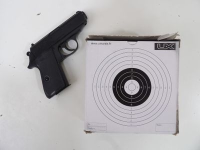 un pistolet et une cible posés sur une table blanche