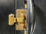 black leather suitcase with gold hardware and lock on it
