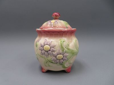 un pot en céramique orné de fleurs, posé sur un fond gris