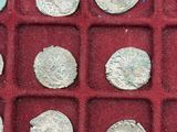 an assortment of silver coins in a red case on a red surface