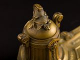 a gold vase with a bird on top of it